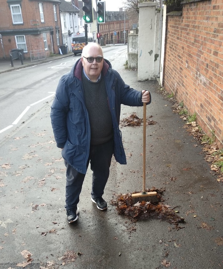 David pictured helping sweep up wet and slippery leaves at corner of Woodbridge Road / Lacey Street